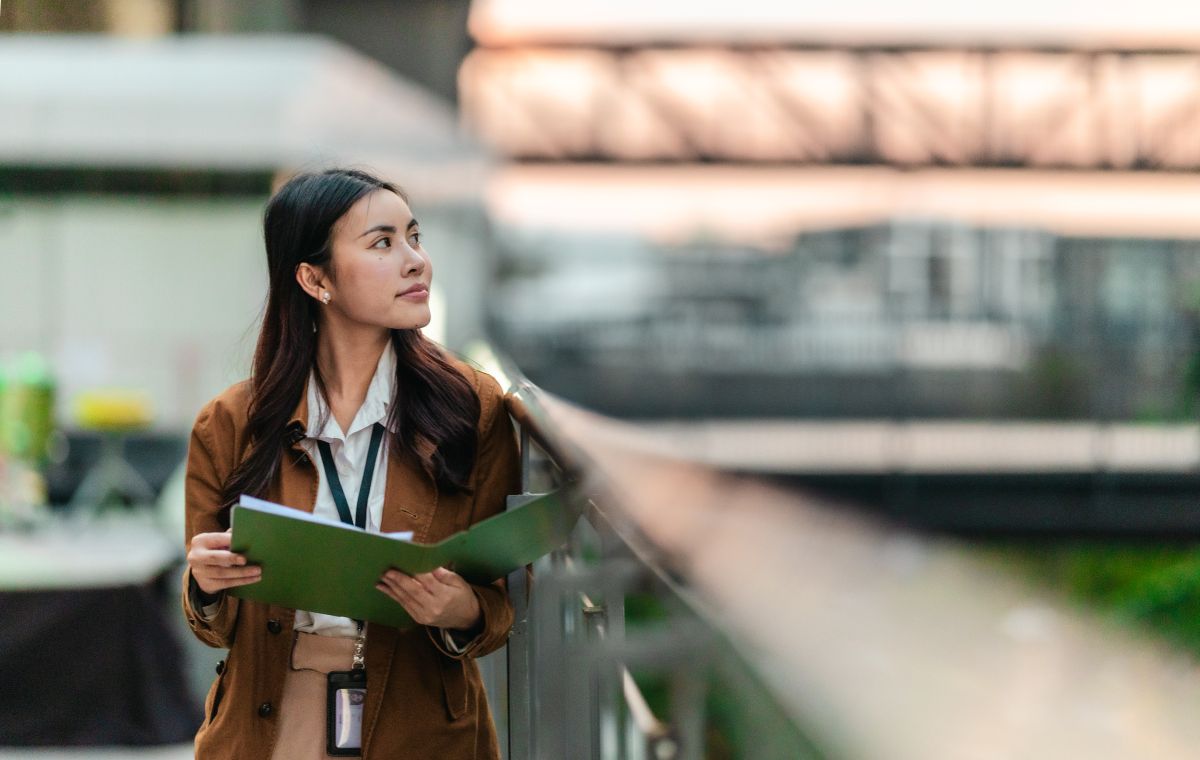 Une femme asiatique portant un dossier vert regarde vesr la droite