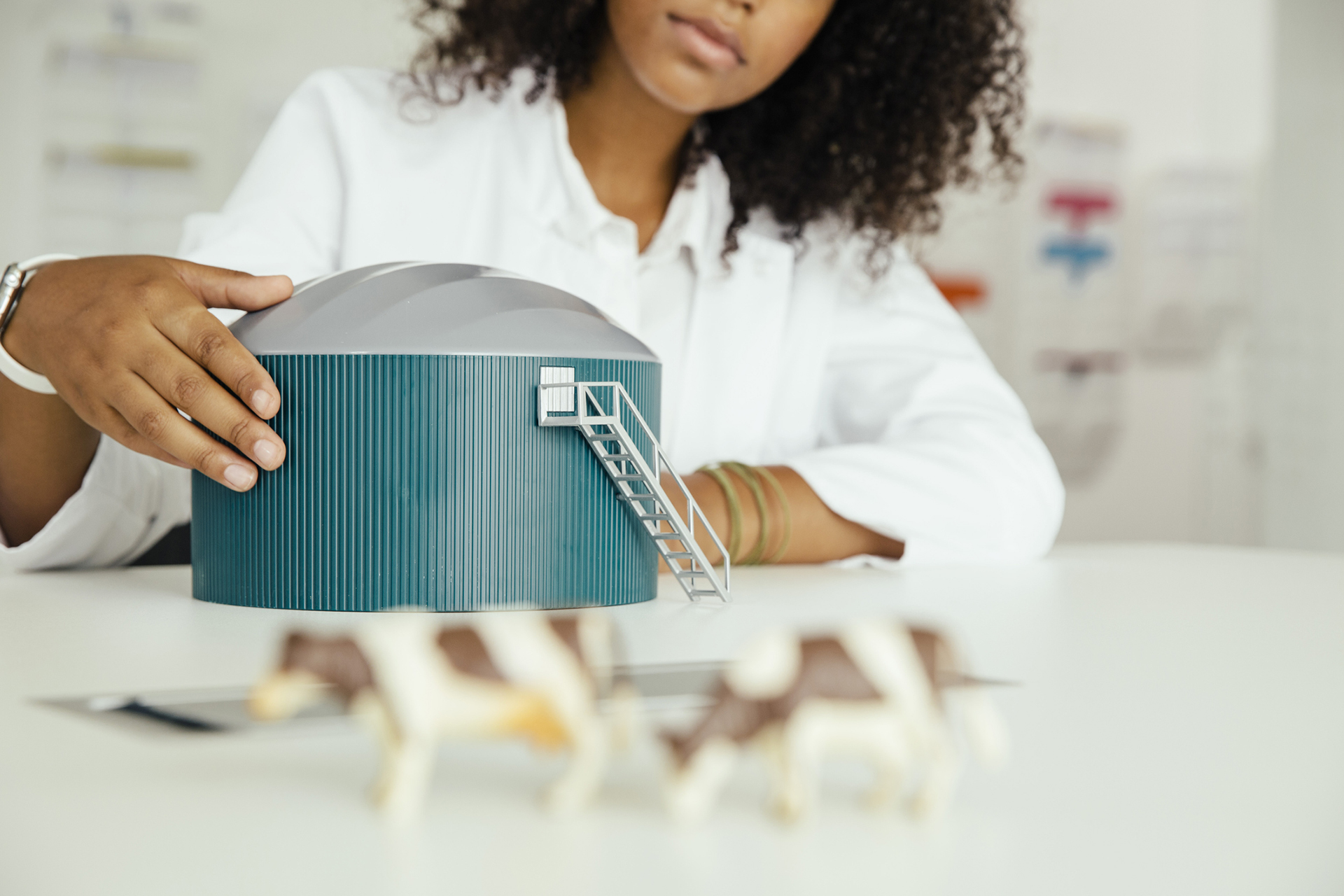 Une femme à la peau mate tient un modèle réduit de méthaniseur