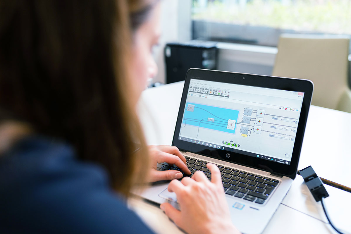 Une femme de dos assises devant son ordinateur portable