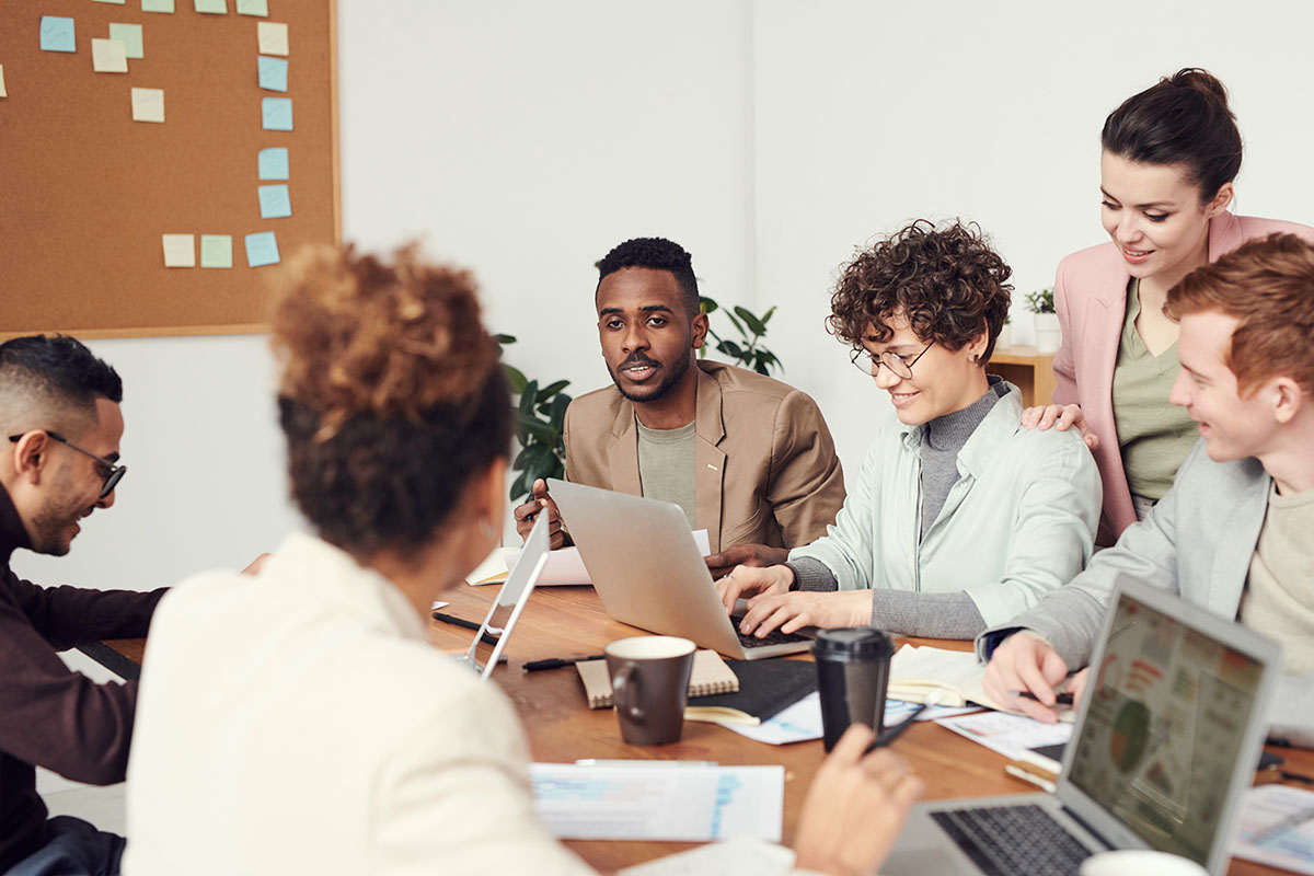 Six people at a meeting table working on their laptops