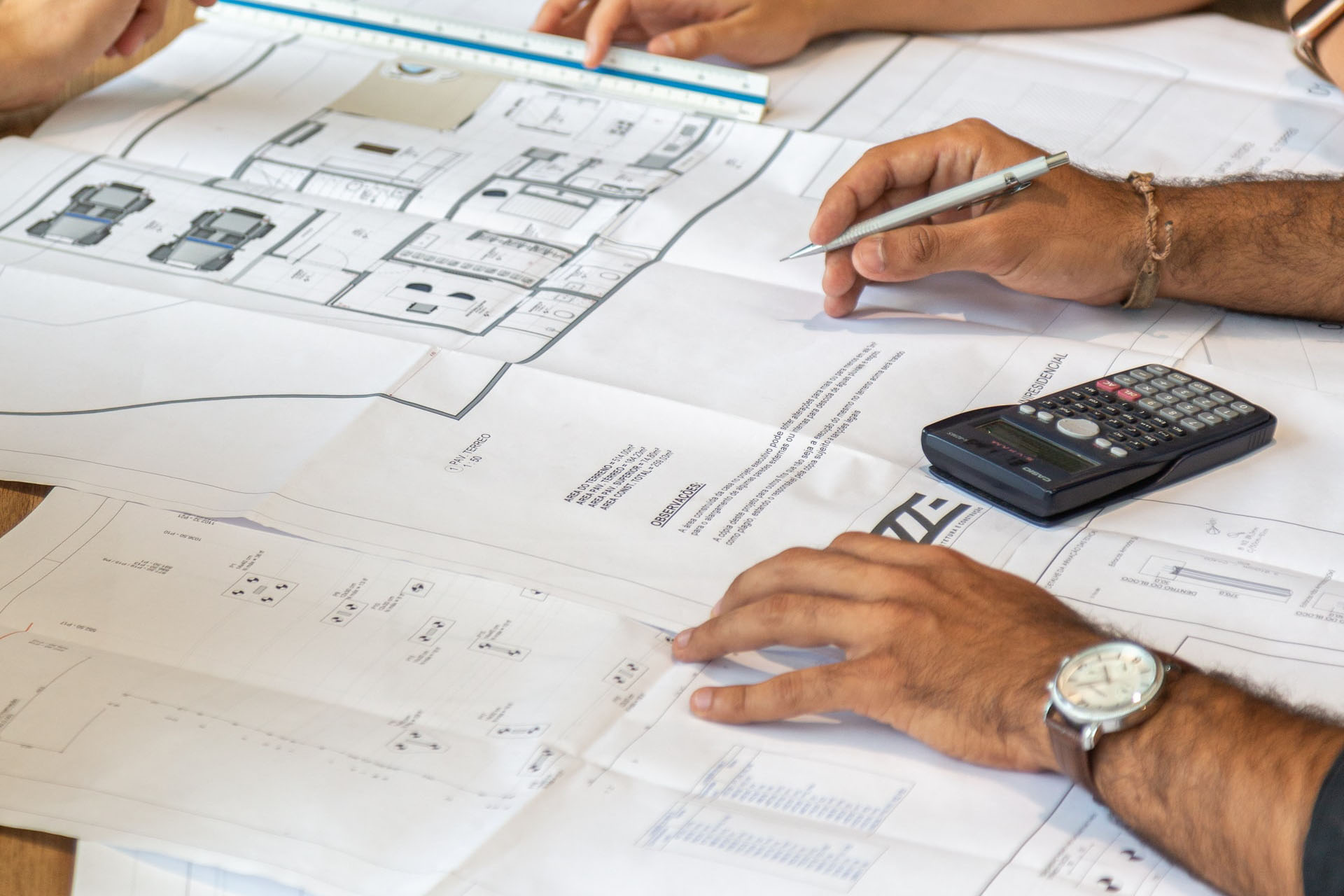 Gros plan sur les mains d'un homme dessinant sur un plan technique