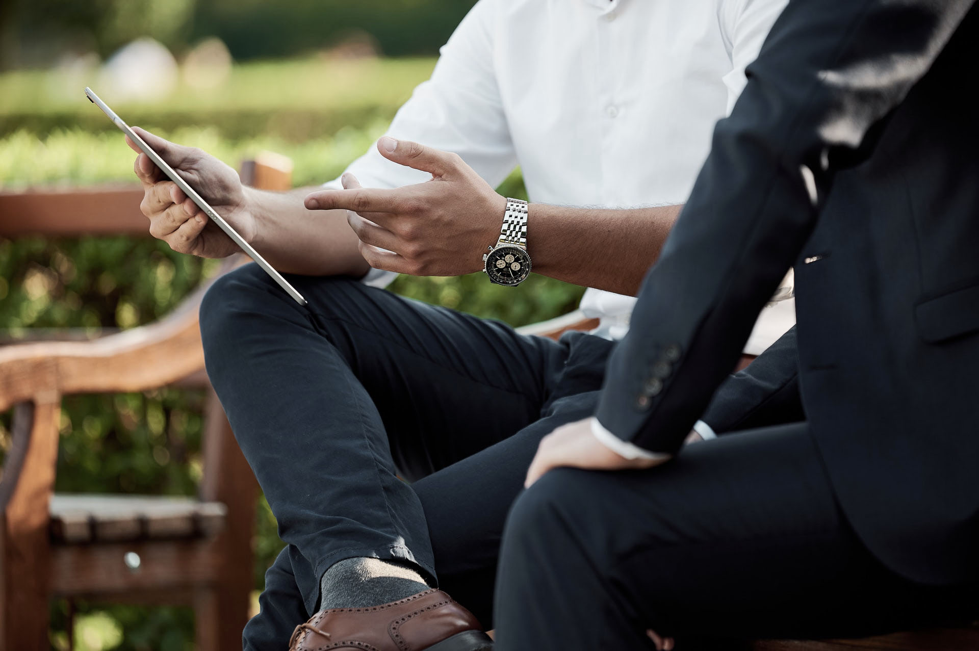 Mains d'une personne assise sur un banc montrant une tablette