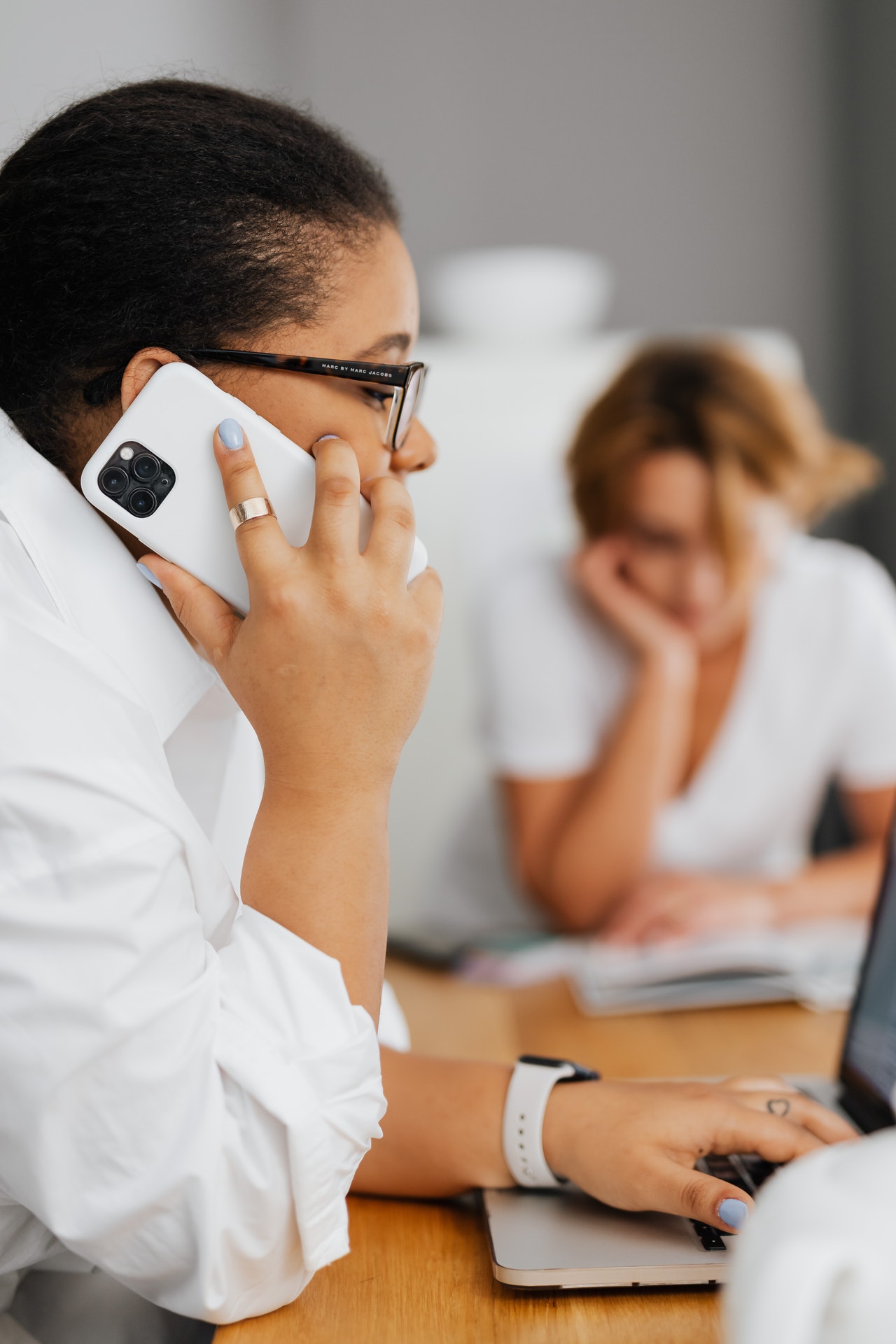 Une femme à la peau mate au téléphone près d'une personne assise à une table de réunion