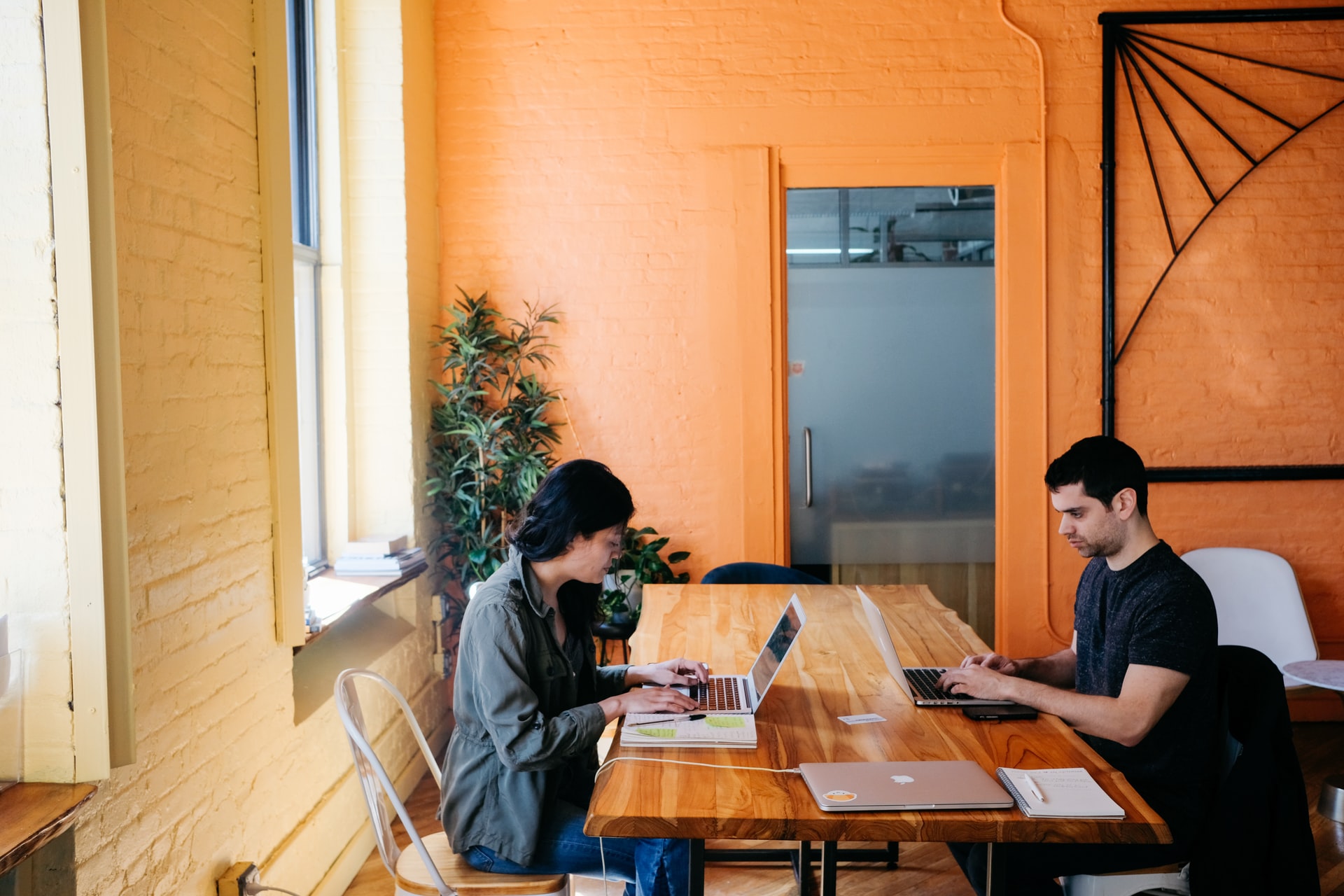 Une femme et un homme assis à une table travaillent sur leur ordinateur
