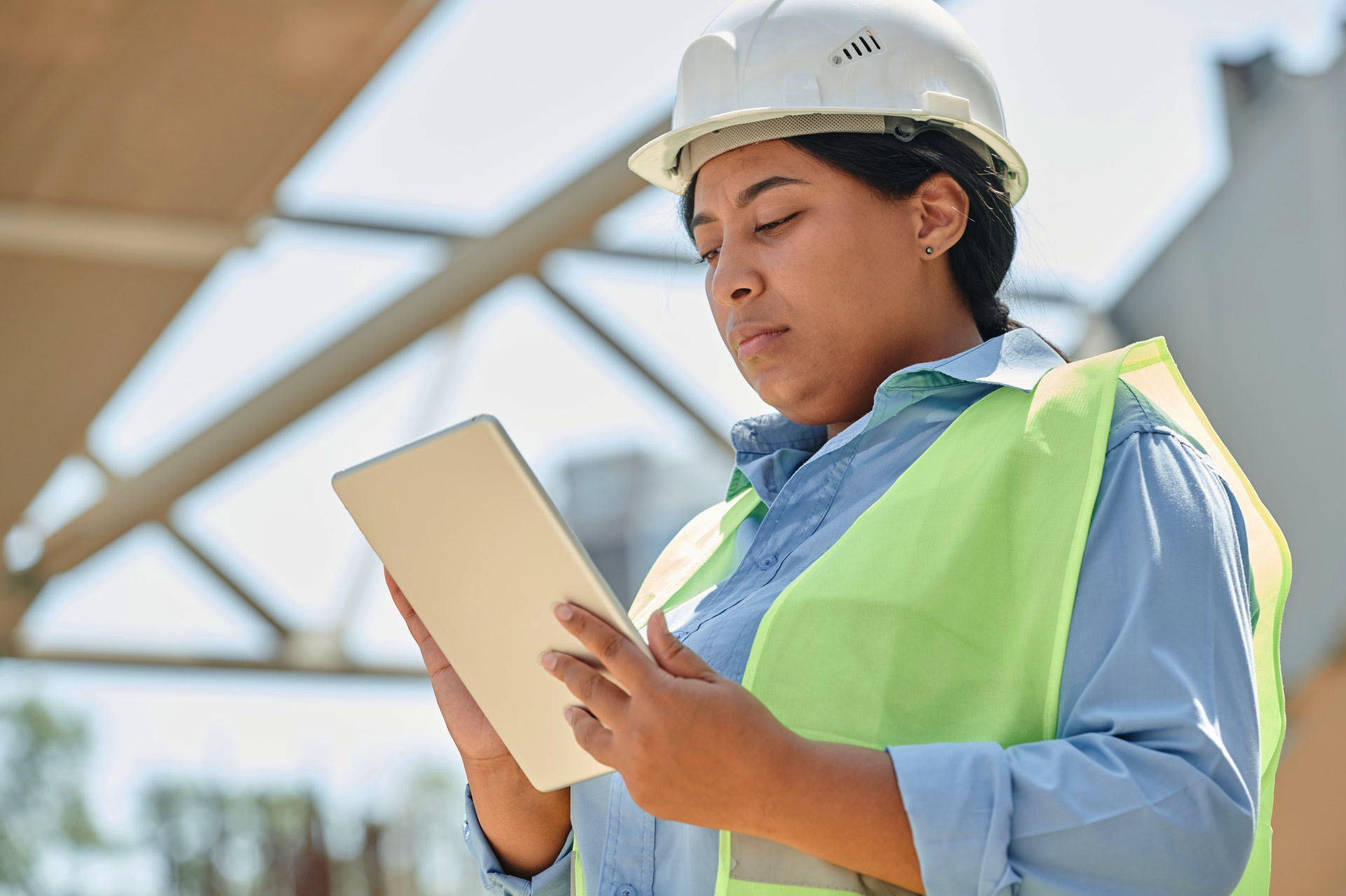 Femme à la peau mate portant un casque de sécurité utilisant une tablette