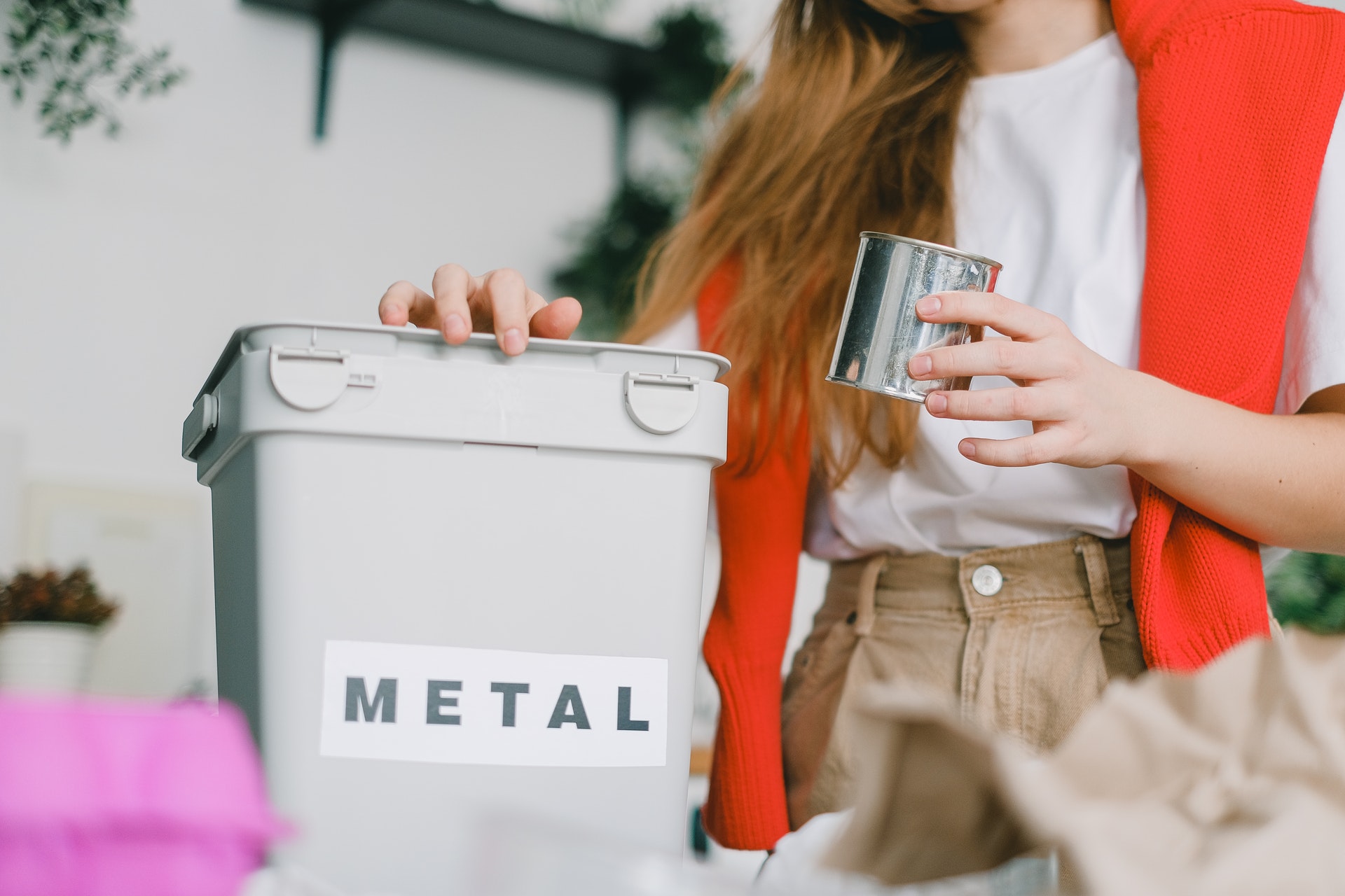 Close-up of a woman's hands throwing a metal can into a recycling bin