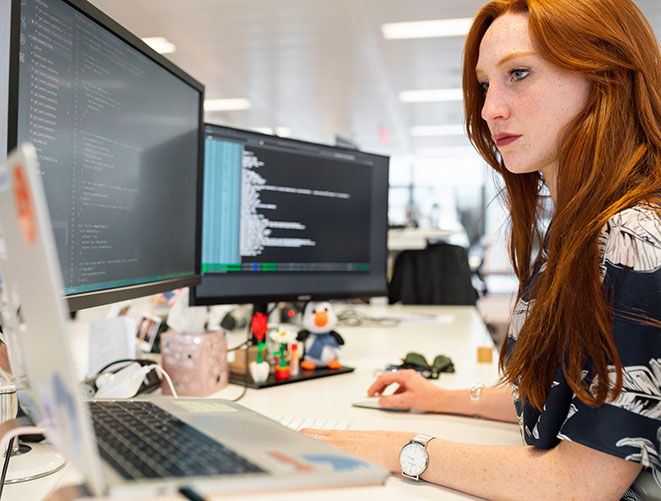 Une développeuse rousse travaille sur son ordinateur