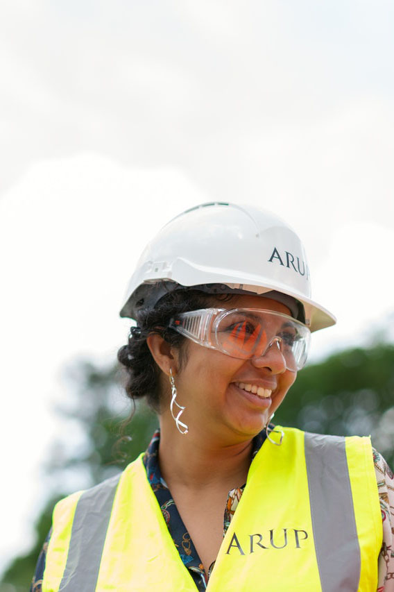 Une femme à la peau mate souriant et portant un casque et des lunettes de protection