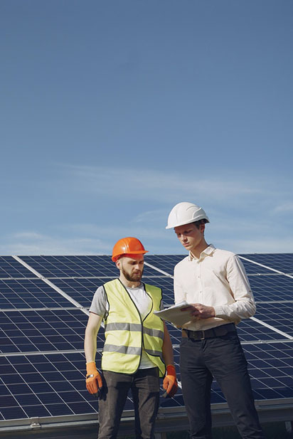 Deux hommes blancs devant des panneaux photovoltaïques consultent une tablette