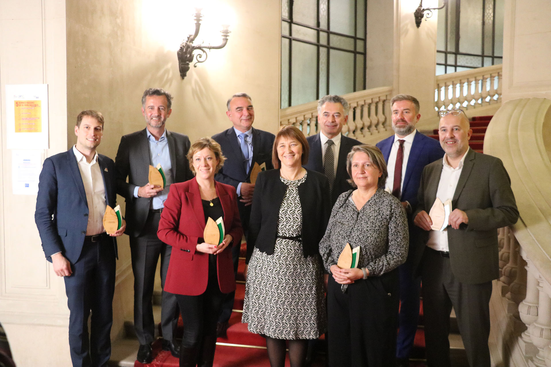 Groupe de neuf personnes debout dans un escalier souriant