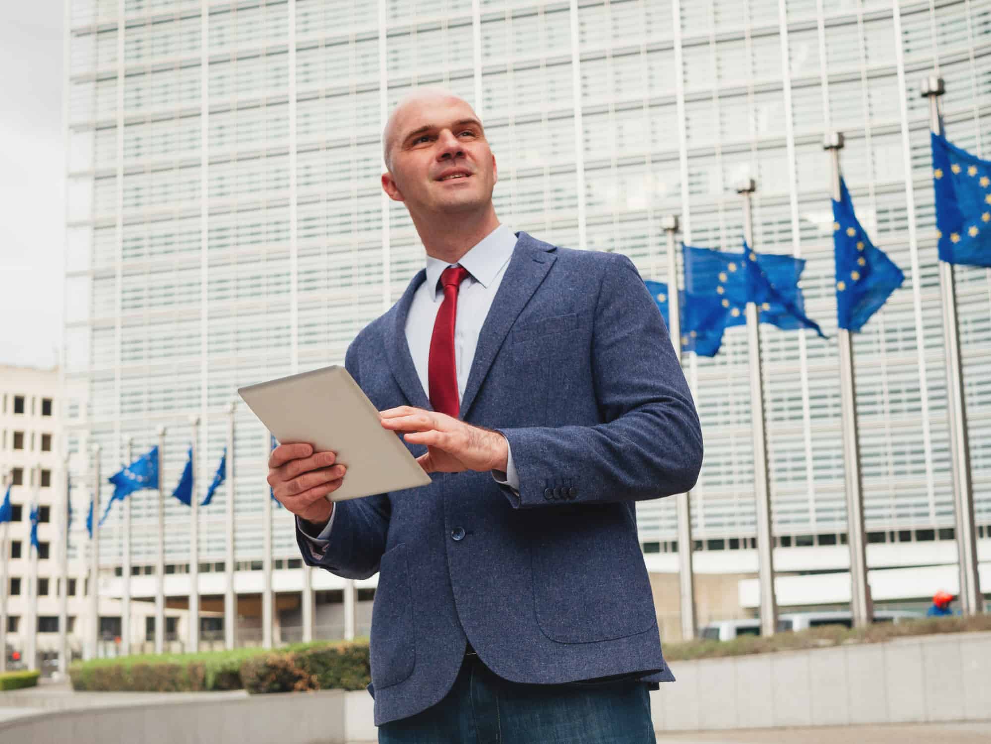 Homme blanc en costume cravate devant le Parrlement Européen