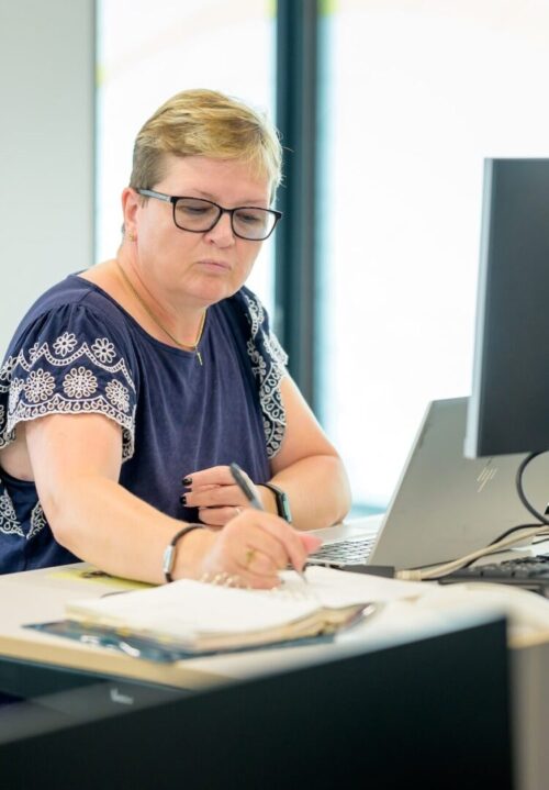Femme blanche debout à un bureau écrivant