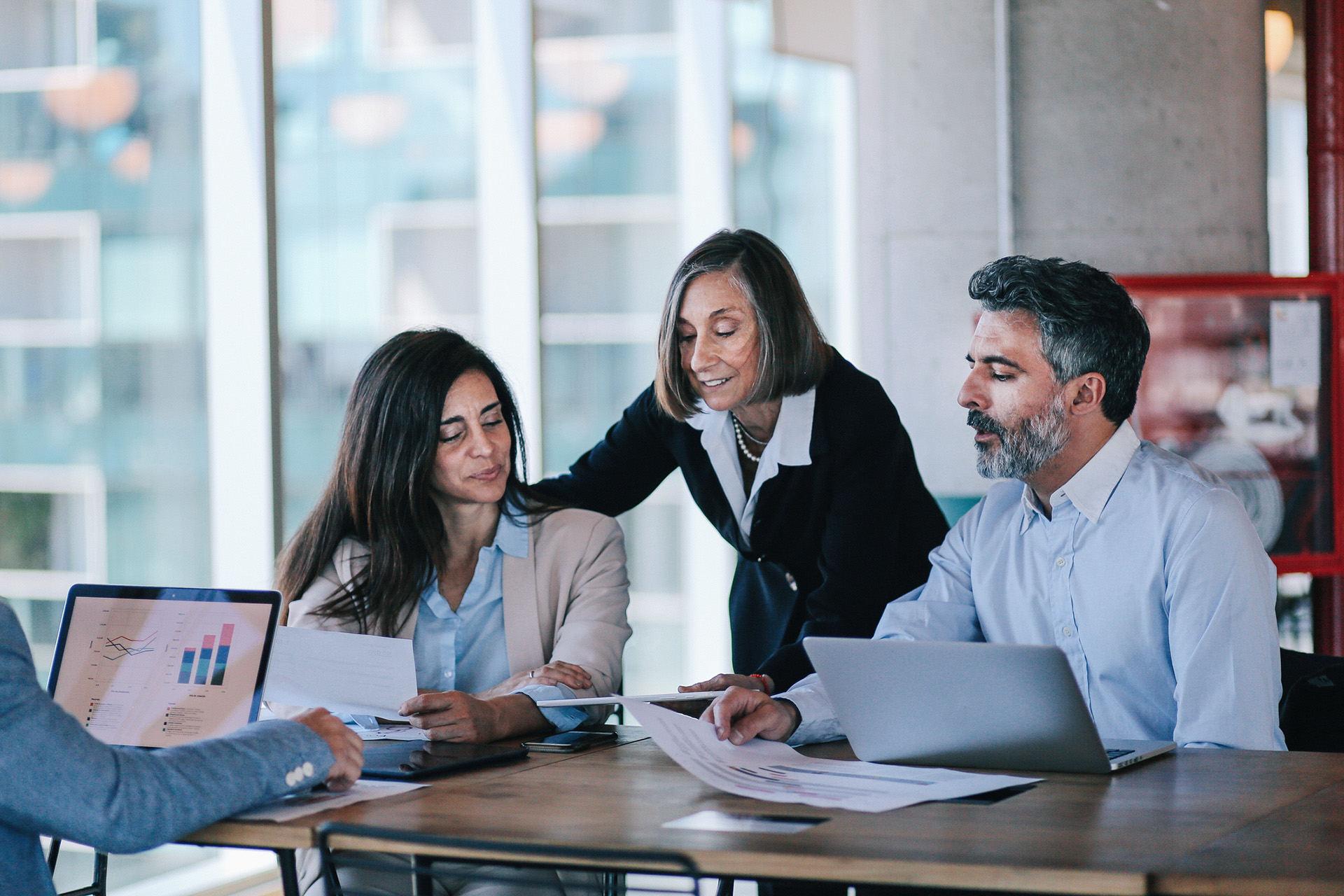 Trois personnes à une table de réunion regardent des documents