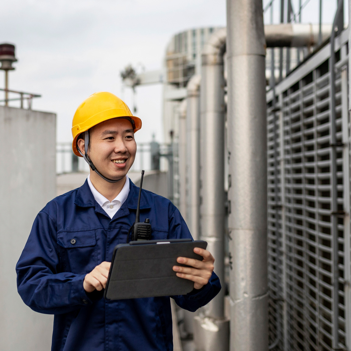 Homme asiatique portant un casque examinant une tour aéroréfrigérante
