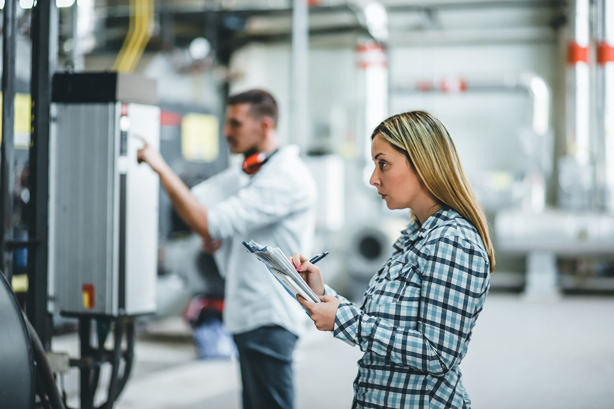 Une femme dans une usine prend des notes sur un carnet