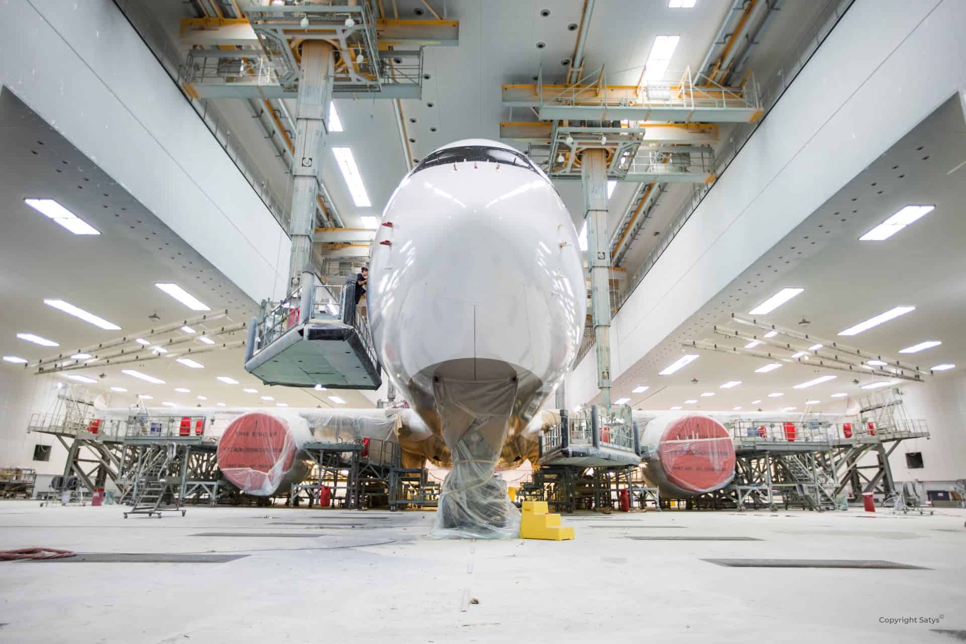 Avion blanc vu de face dans une salle de peinture