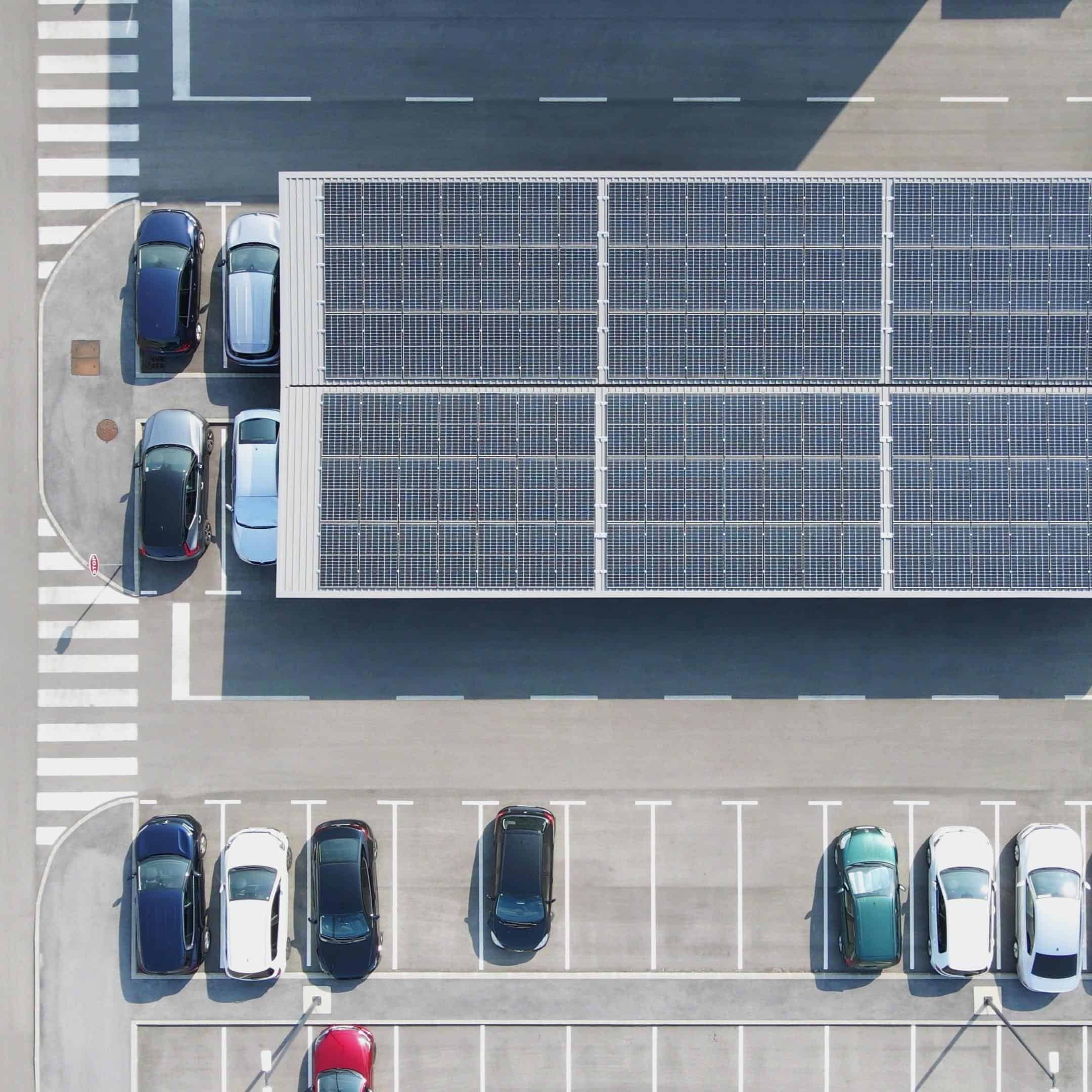 Vue en plongée d'un parking avec des voitures et une ombrières photovolatïque