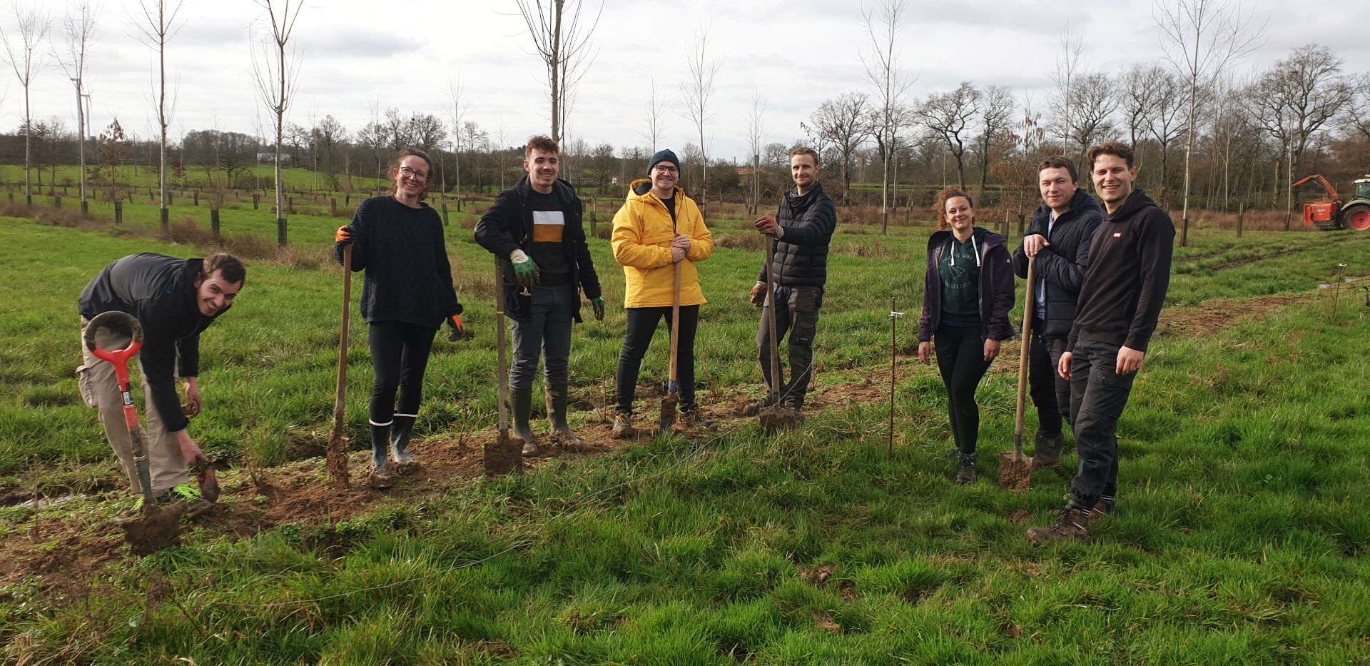 8 personnes dans un champ une personne creuse avec une pelle