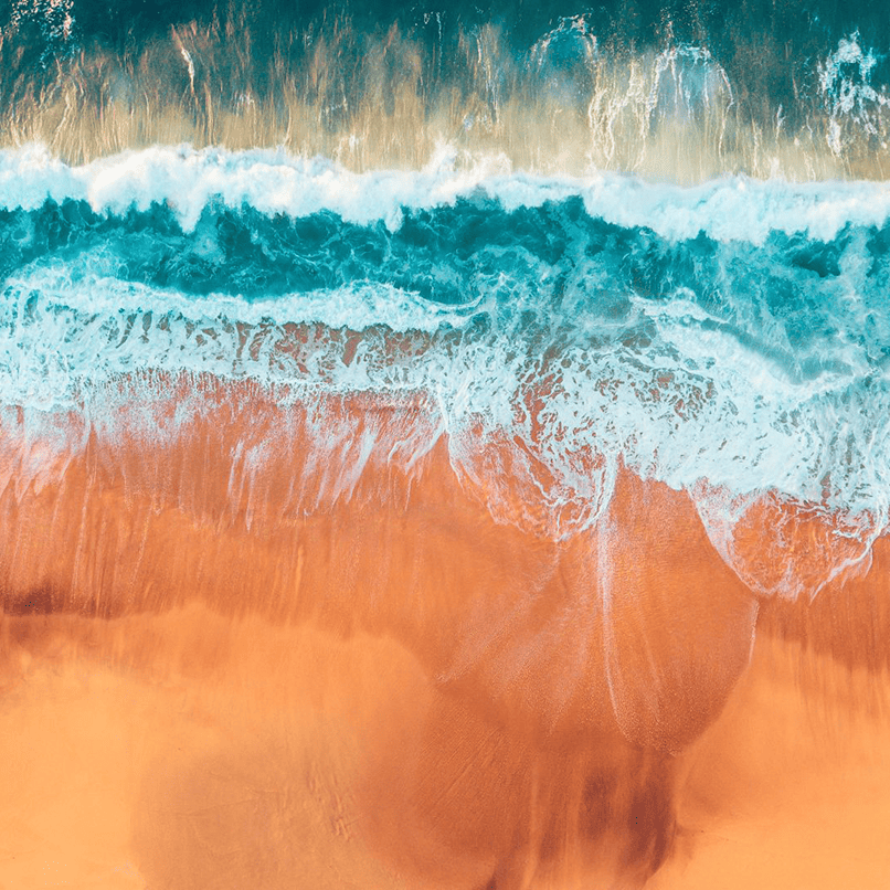Vue aérienne d'une plage de sable orangé et des vagues bleues turquoise